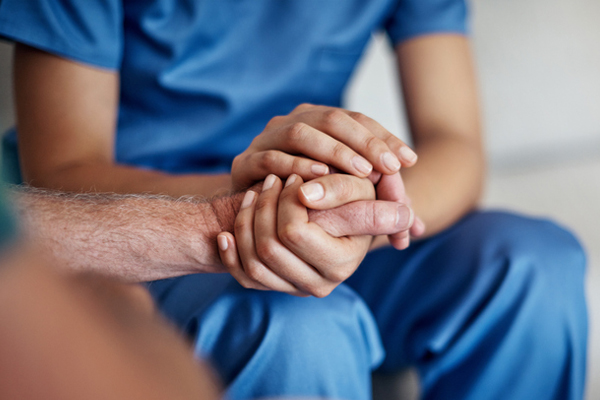 Pfleger hält Hand der betreuten Person. Foto: shapecharge