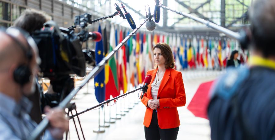 Bundesministerin Edtstadler in Brüssel bei einem Interview, vor Mikrofonen