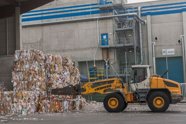 Une pelleteuse ramassant des ballots de cartons afin de les charger dans un camion pour le projet SORT-IT