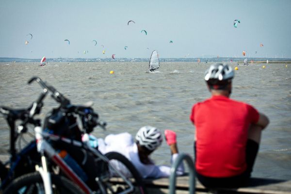 Zwei Radfahrer sitzen auf einem Weg, der sich neben einem Gewässer befindet