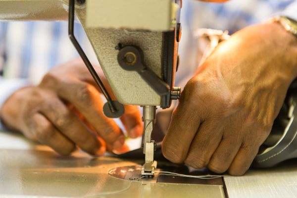 Abbildung: Eine Person benützt eine Nähmaschine