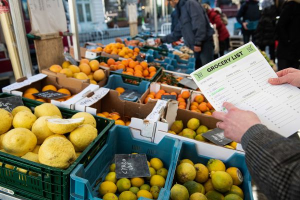 Kontrolleur mit Liste bei einem Marktstand mit Obst und Gemüse