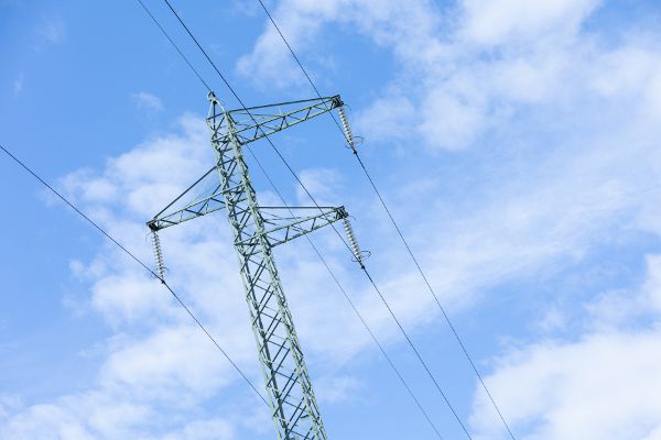Strommasten vor einem blauen, leicht bewölktem Himmel