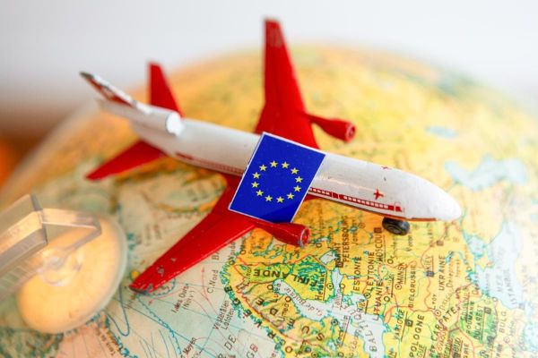 Spielzeugflugzeug auf Globus mit EU-Flagge abgebildet