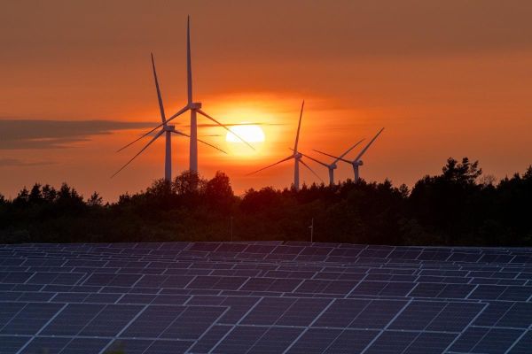 Photovoltaikanlagen und Windräder vor einem stimmungsvollen Sonnenuntergang