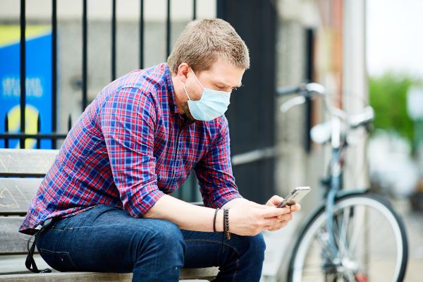 Mann mit Mund-Nasen-Schutz und Handy