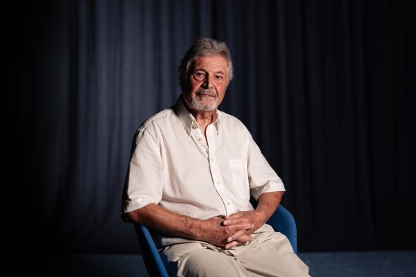 Adolf Silberstein sitzt in einem weißen Hemd auf einem Stuhl.