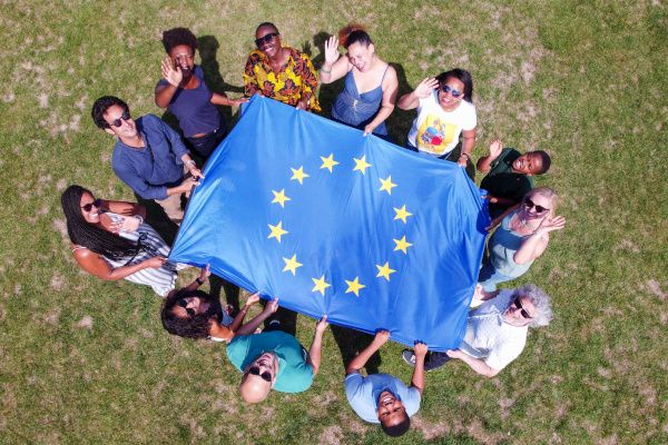 Freundesgruppe in einem Park mit der Flagge der Europäischen Union