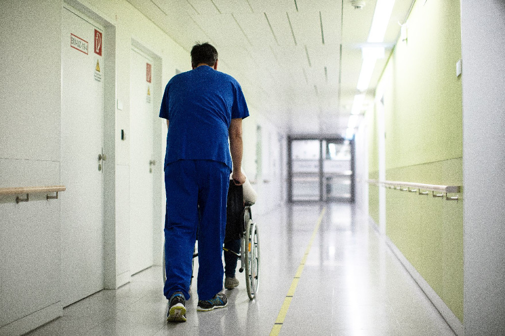 Gang - ein Krankenpfleger schiebt einen Patienten im Rollstuhl