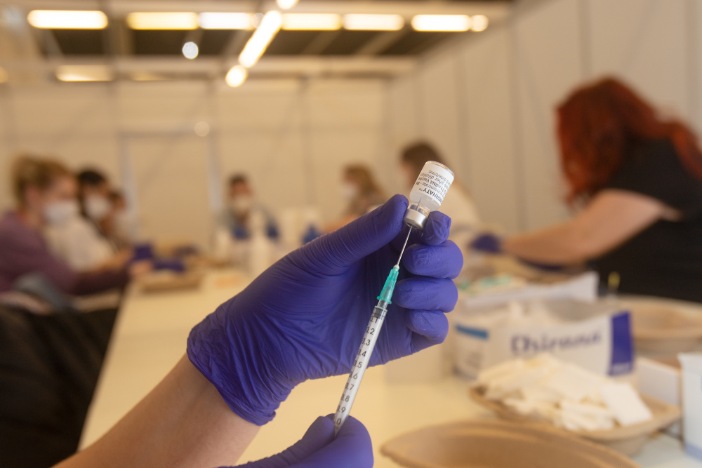 Mitarbeiter befüllt eine Spritze mit einer Dosis eines Covid-19 Impfstoffes