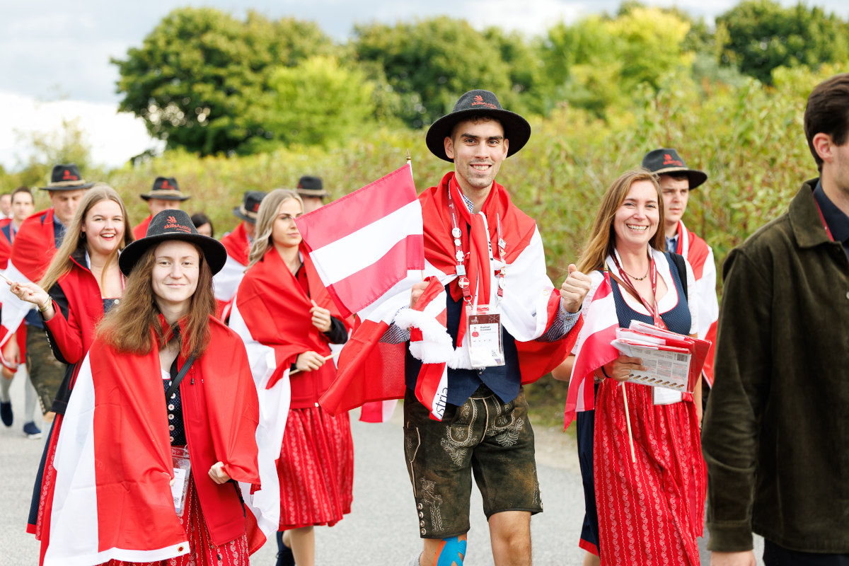 Teilnehmerinnen und Teilnehmer aus Österreich in Tracht und Bundesflagge