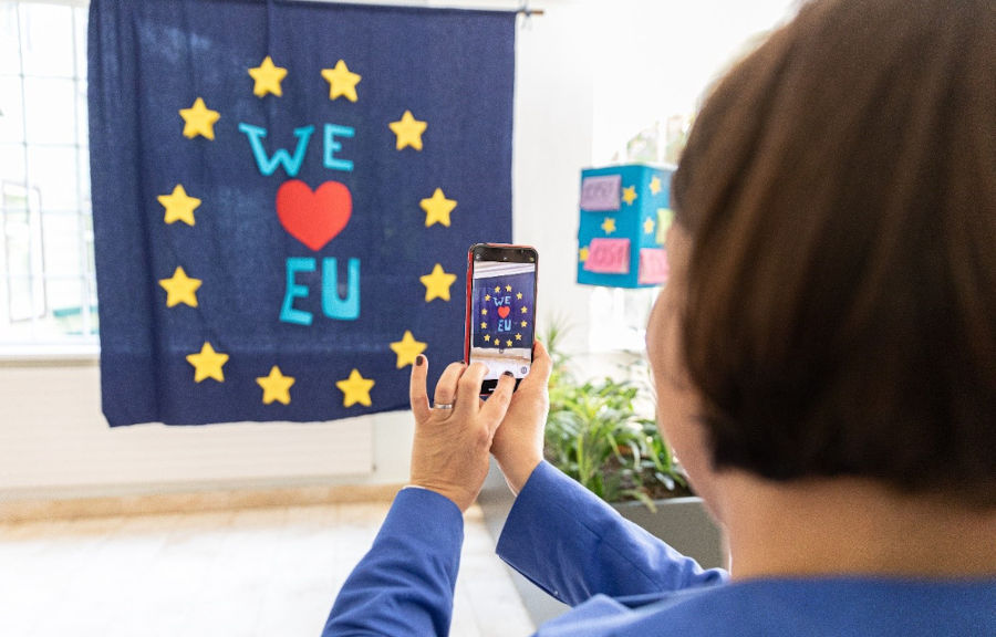 Eine Frau macht mit einem Smartphone ein Foto von einer Europa-Flagge