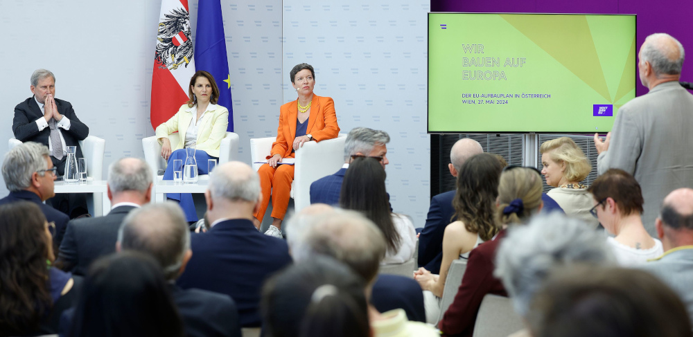 Fachtagung "Wir bauen auf Europa": EU-Kommissar Hahn, Europaministerin Edtstadler und eine Moderatorin (am Podium) hören einer fragenden Person aus dem Publikum zu