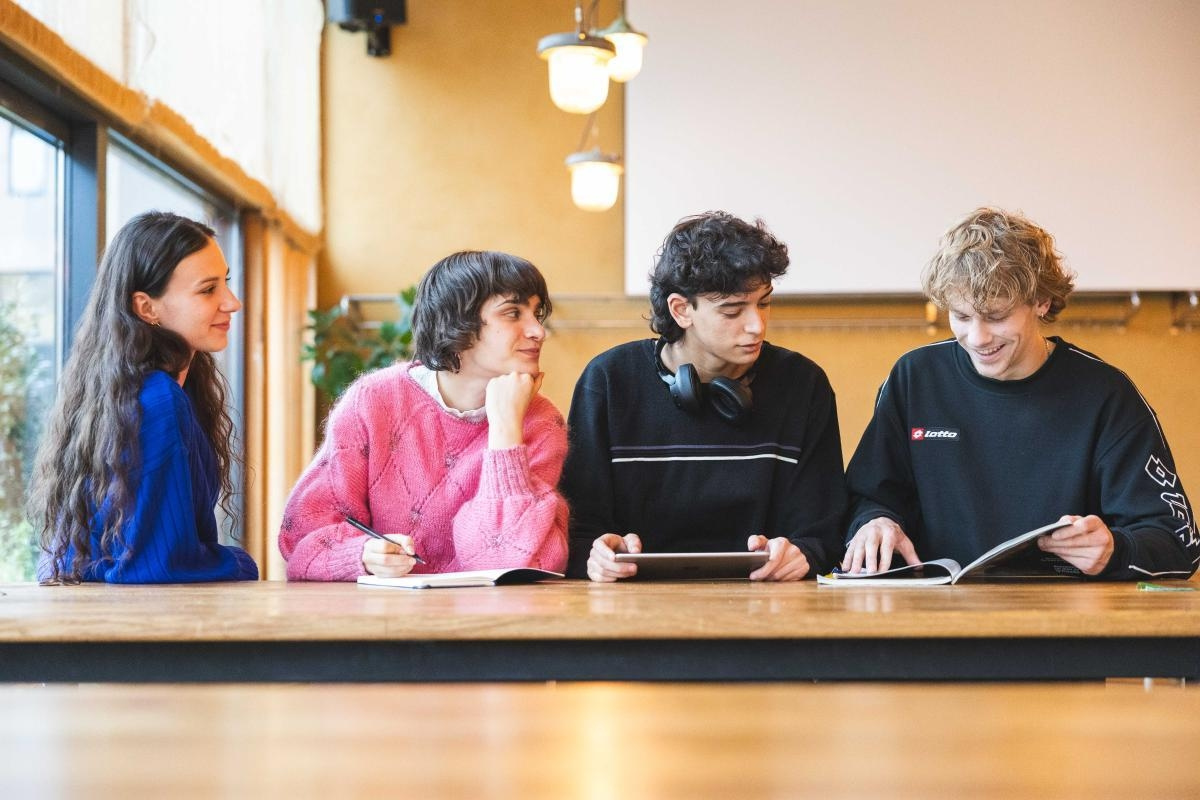4 Trainees sitzen an einem Tisch und blättern in ihren Unterlagen