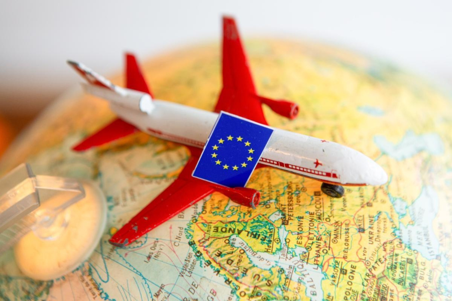 Spielzeugflugzeug auf Globus mit EU-Flagge abgebildet