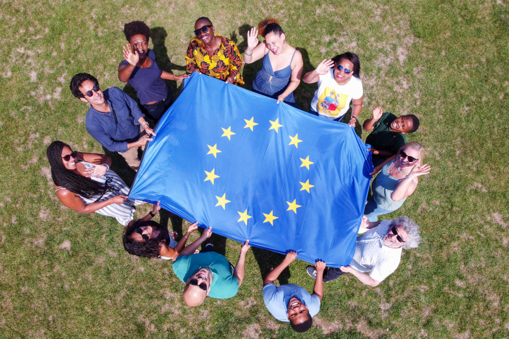 Gruppe von Freundinnen und Freunden mit der Europafahne von oben fotografiert