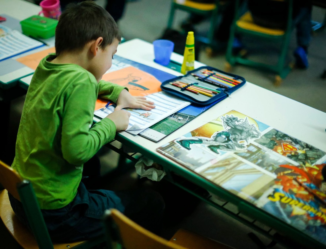 Ein Kind sitzt in einer Schule und schreibt in ein Heft.