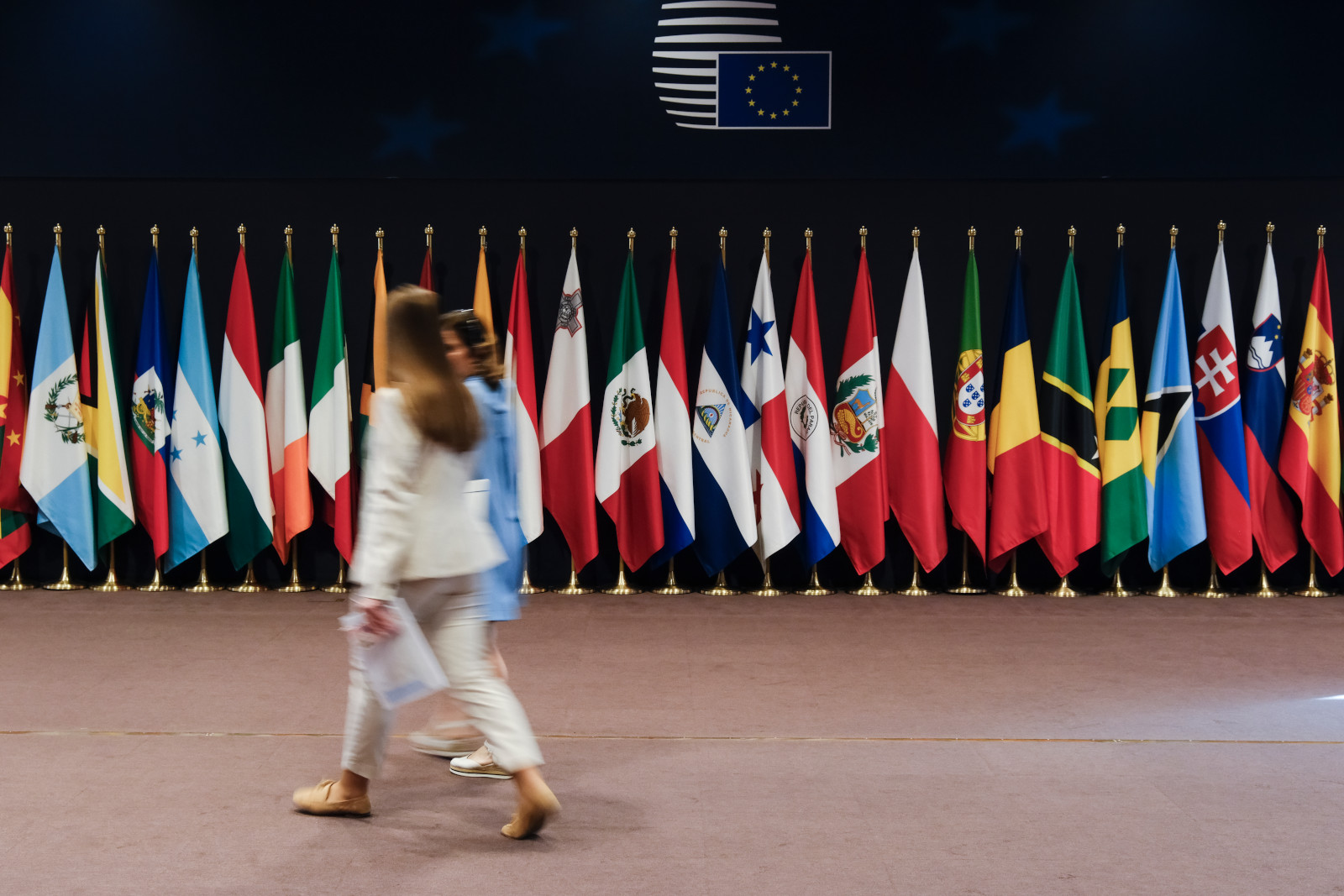 2 Frauen gehen vor den Länderfahnen beim EU-Lateinamerika Gipfel entlang. Foto: Europäische Kommission