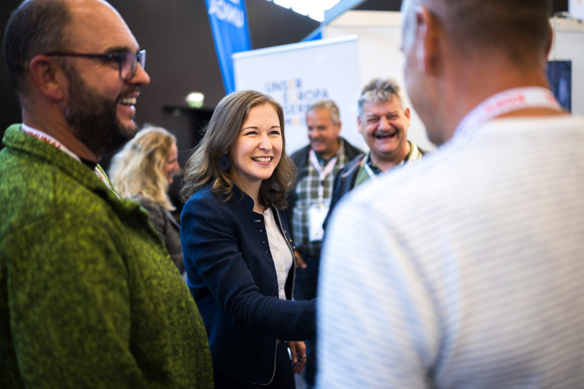 Claudia Bauer begrüßt Besucher am Stand des Bundeskanzleramtes