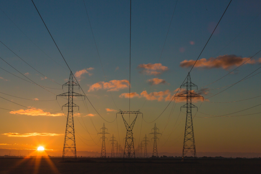 Freileitungsmasten mit Sonnenuntergang im Hintergrund