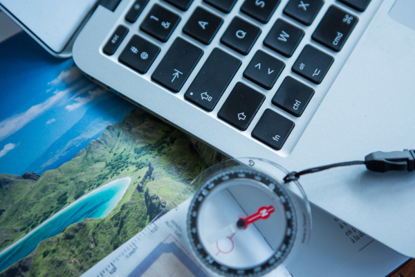 Symbolfoto für Urlaubsplanung mit Computer und Kompass