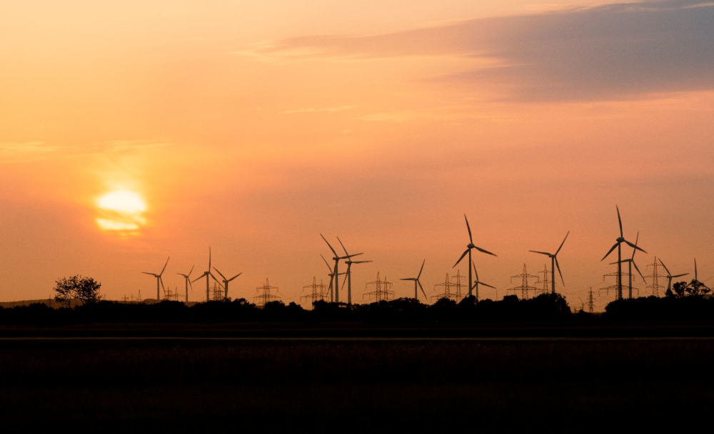 Windräder während eines Sonnenuntergangs im Hintergrund